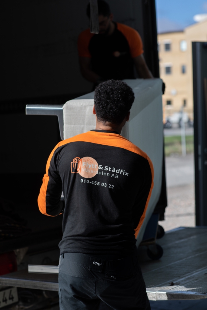 Medarbetare från Flytt och städfix Mälardalen AB lastar en säng till en bil under en flytt.