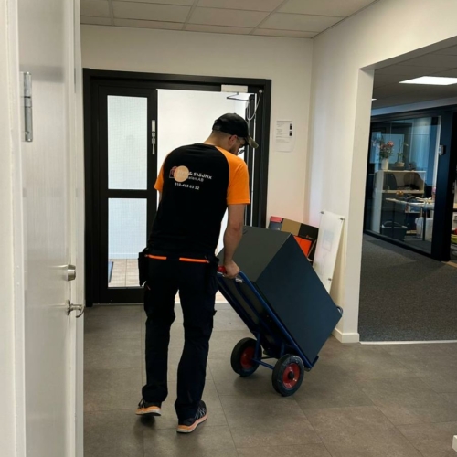 Medarbetare från Flytt och städfix Mälardalen AB flyttar ett kassaskåp med hjälp av en kärra.